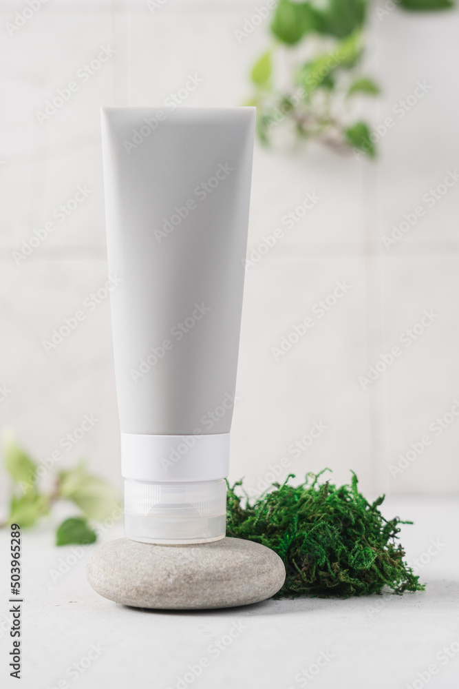 Cosmetic bottle on a pebble stone surrounded by natural moss, green leaves. Natural cosmetic background for product presentation Cosmetic bottle on a pebble stone surrounded by natural moss, green leaves. Natural cosmetic background for product presentation