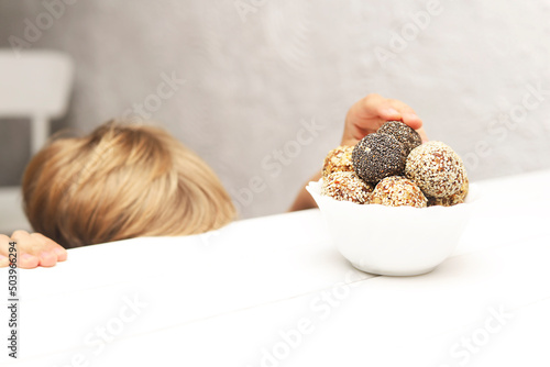 Child hands stealthily taking energy balls in the kitchen.