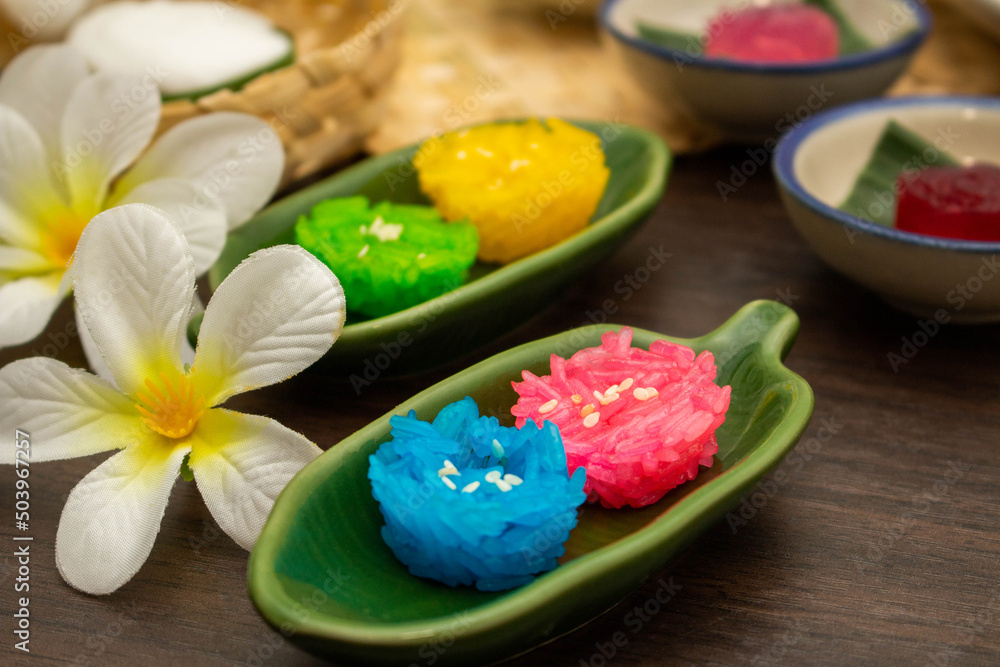 Thai traditional dessert concept, Colorful glossy sticky rice on banana leaf plate on wooden table