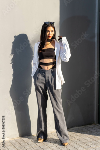Fashionable concept, Fashion woman is posing near gray wall while in gray pants and white shirt