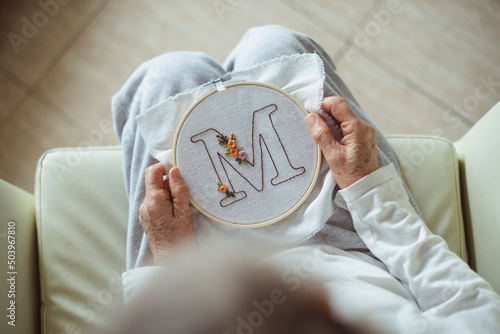Overhead view of a woman holding an embroidery hoop with the letter M