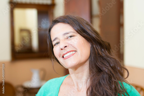 Attractive middle-aged woman looking, smiling in the house.