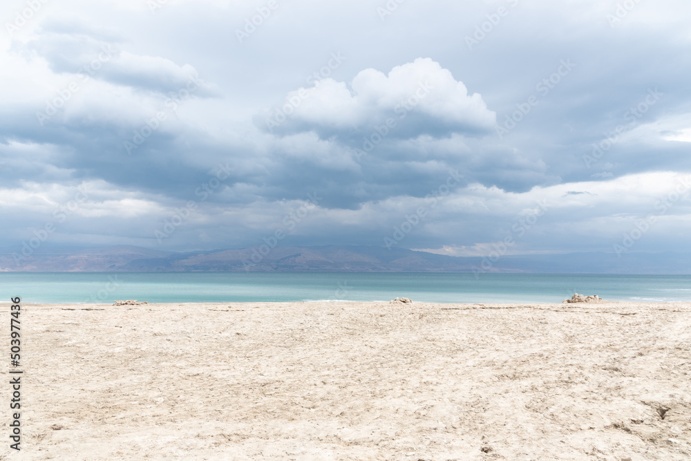 Exotic view of the sinkhole area of the Dead Sea on a stormy winter day. PhotoStorm and rain at the Dead Sea coastline. Salt crystals at sunset. The texture of the Dead sea. Salty seashore. High