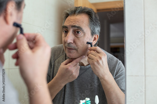 senior man shaving in front of the mirror
