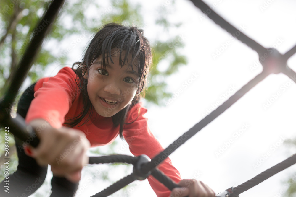 Cute little girl toddler having fun on the playground, climbing and sliding down Cute little girl toddler having fun on the playground, climbing and sliding down