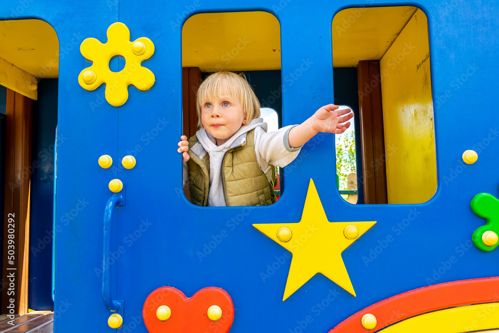 Cute funny blond little young toddler kid child boy riding in toy car