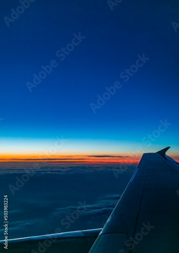 Sunset outside the porthole of an airplane © 大 李
