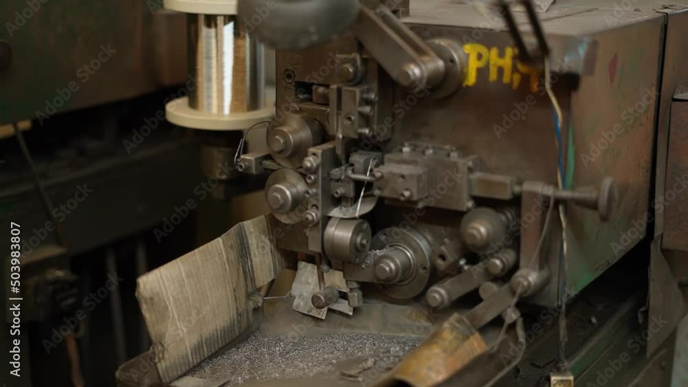 Wide shot of an old rusted machine producing spring from the steel wire, Automatic industrial conveyor machine for the manufacture of parts from steel wire Wide shot of an old rusted machine producing spring from the steel wire, Automatic industrial conveyor machine for the manufacture of parts from steel wire