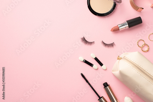Make-up beauty concept. Top view photo of compact powder gold rings bracelet lipstick false eyelashes brushes mascara and cosmetic bag on pastel pink background with empty space