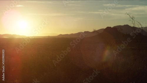 View of the bright scorching sun in the desert among the mountain slopes, bright rays glare light in all directions, hot summer evening, wild west atmosphere. HD footage 
