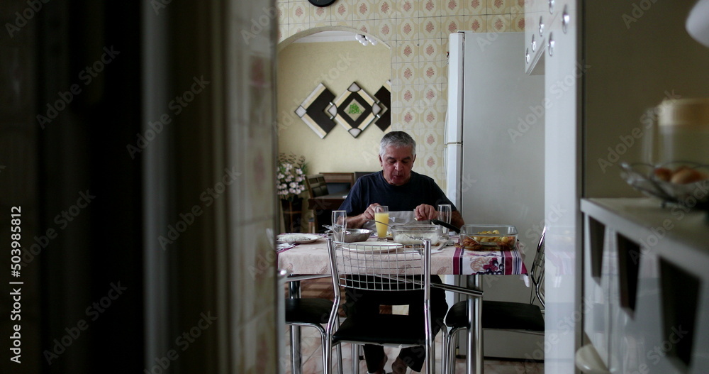 © Marco - Lonely older man eating lunch alone in home kitchen