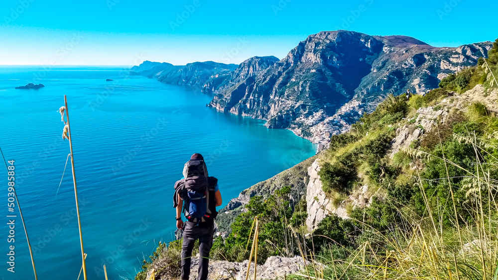 Man with panoramic view from hiking trail Path of Gods between coastal towns Positano and Praiano. Trekking in Lattari Mountains, Apennines, Amalfi Coast, Campania, Italy, Europe. Mediterranean Sea