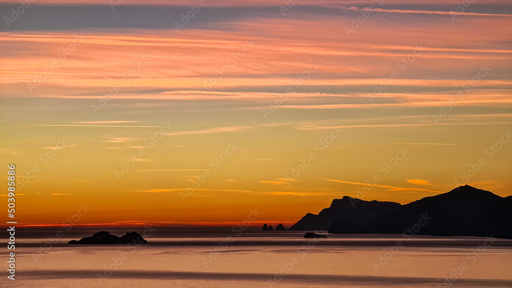 Panoramic sunset view from Praiano at Mediterranean Sea, Italy, Campania, Europe. Silhouette of Li Galli islands and coastline of Amalfi Coast. Reflection of sun beams on water surface during twilight