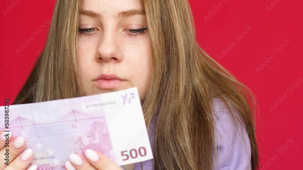 Close-up Caucasian young woman 20 years old examines a paper banknote of 500 euros. A European girl is holding a 500 euro banknote. selective focus Close-up Caucasian young woman 20 years old examines a paper banknote of 500 euros. A European girl is holding a 500 euro banknote. selective focus