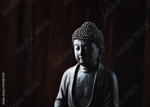 Meditating Buddha Statue on dark background. Soft focus. Close up. Copy space.