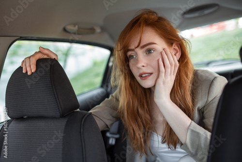 scared woman holding hand on head while riding in car on blurred foreground © Graphicroyalty