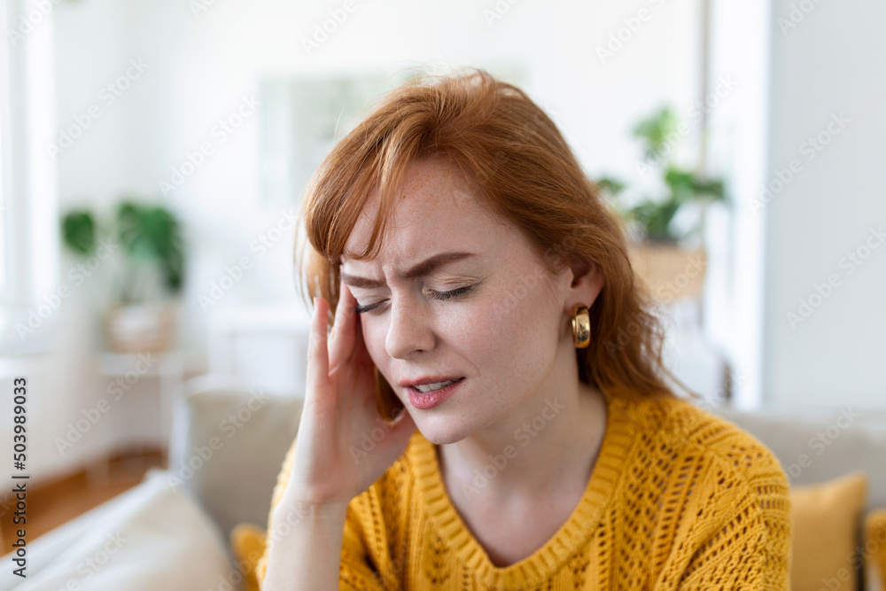 Closeup view frown face of woman feeling strong headache touch temple to reduce severe pain, suffering from panic attack in office, migraine overworked person or hangover alcohol abuse concept Closeup view frown face of woman feeling strong headache touch temple to reduce severe pain, suffering from panic attack in office, migraine overworked person or hangover alcohol abuse concept