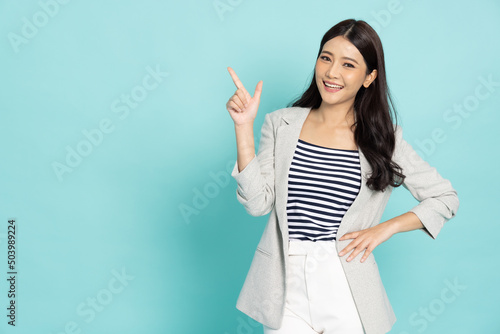 Young beautiful Asian business woman pointing to empty copy space isolated on green background photo