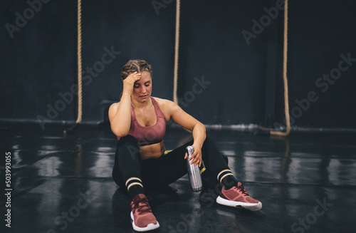 Quadro su tela Caucasian female in tracksuit holding sport water bottle for refreshing during b