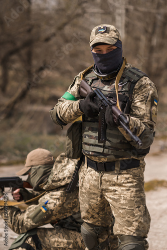 Two Ukrainian soldiers in uniforms aim from a Kalashnikov assault rifle