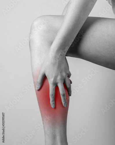 Shin pain. Woman holding leg with red spot. Tendons, muscles inflammation, injury, bone bruise consequences. Black and white. High quality photo photo