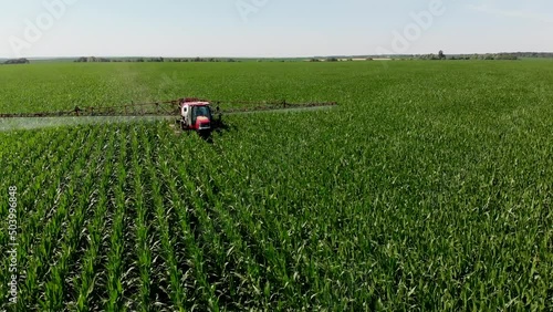 A tractor sprayer sprays corn in the field. Shooting from a 4K drone. Spraying of chemical fertilizers on an agricultural field