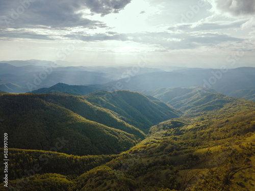 High angle aerial view drone image of sunset sun rays trough the trees and forest in mountain range in autumn or winter day - Babin Zub Old Mountain in Serbia - Travel journey and vacation concept photo