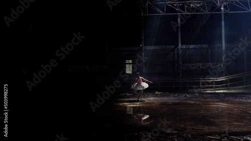 Graceful ballerina wears pointe shoes under the light that shines down on the roof hatch from the wash hall. Flexible ballet dancers dance in a classic tutu. Gorgeous ladies enjoying a classic indoor  photo