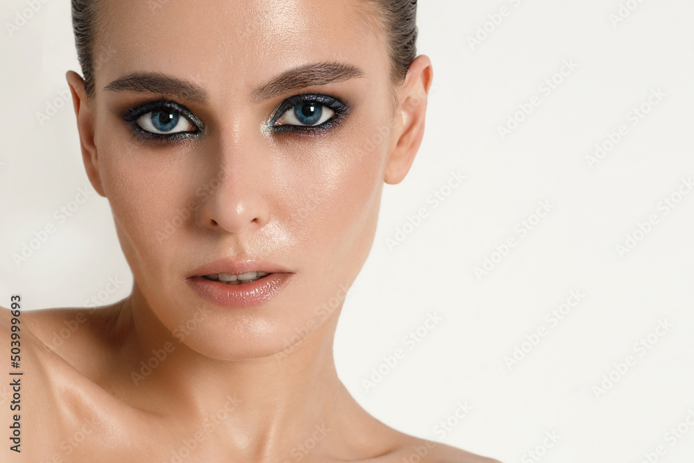 Fototapeta premium Portrait of an adult woman with makeup and smooth wet hairstyle on a white background skin care concept, perfect skin.