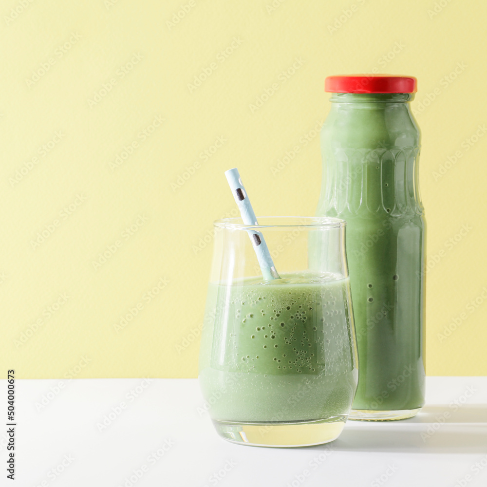 healthy green smoothie in glass, bottle with straw on yellow background. Vegetarian healthy lifestyle concept.refreshing drink. quick snack. square healthy green smoothie in glass, bottle with straw on yellow background. Vegetarian healthy lifestyle concept.refreshing drink. quick snack. square