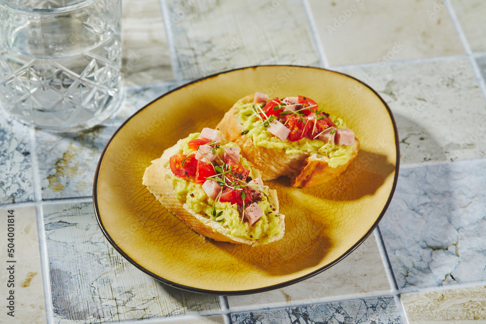 Crostini or bruschetta with softened avocado, ham and tomatoes. Toast with mashed avocado Crostini or bruschetta with softened avocado, ham and tomatoes. Toast with mashed avocado