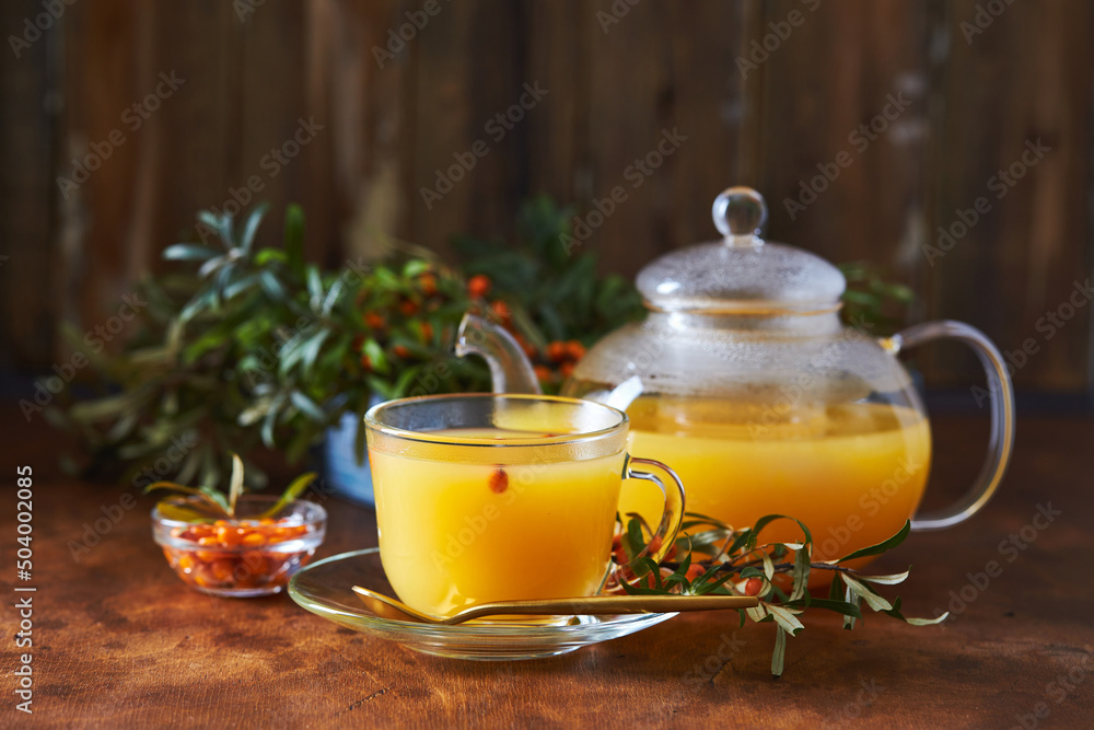 Glass teapot and sea buckthorn tea cup on wooden background Glass teapot and sea buckthorn tea cup on wooden background