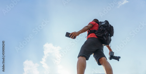 A MAN WALKING WITH A CAMERA IN HAND AND A SMART PHONE