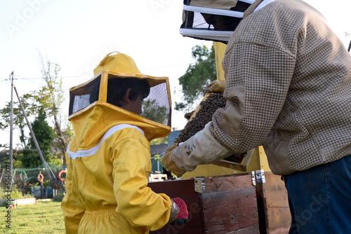 father teaches his son the art of beekeeping