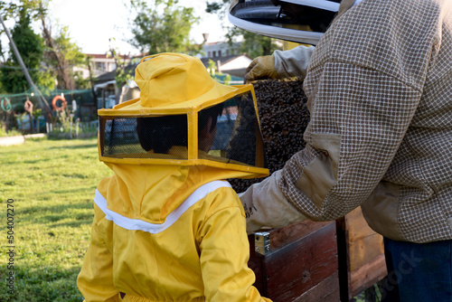 father teaches his son the art of beekeeping