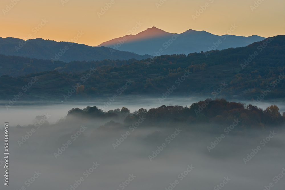 Moments before sunrise over the mountains with the valley covered by deep mist. Mountains landscape