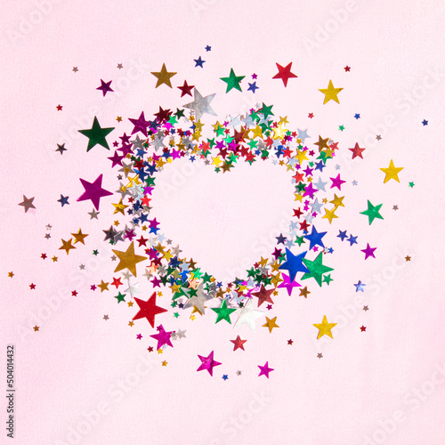 Heart shaped copy made of colorful stars on pastel light pink background.  Creative magic love idea. Modern Valentine s day concept.