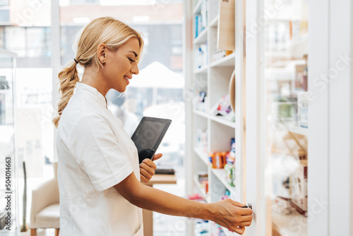 Young and attractive female pharmacist working in a drugstore. She is happy and smiled.
