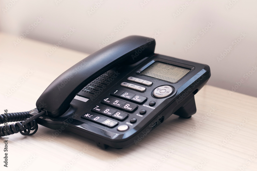 Black office phone on the wooden table. Communication technology concept. Black office phone on the wooden table. Communication technology concept.