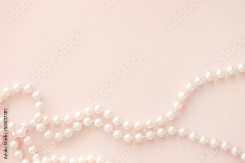 Pearl beads on pastel pink horizintal background with copy space.