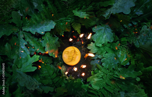 amulet of symbolic sun-moon, burning candles, oak leaves on natural forest background. Pagan, Wiccan, Slavic traditions. Witchcraft, esoteric ritual for Summer Solstice Day, Midsummer, Litha holiday