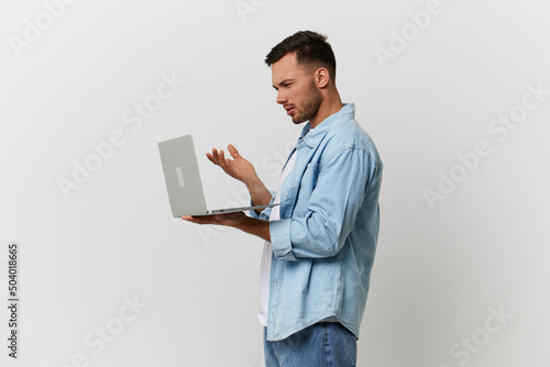 Unhappy irritated tanned handsome man in casual basic t-shirt have problem with broken laptop posing isolated on over white studio background. Copy space Banner Mockup. Electronics repair IT concept