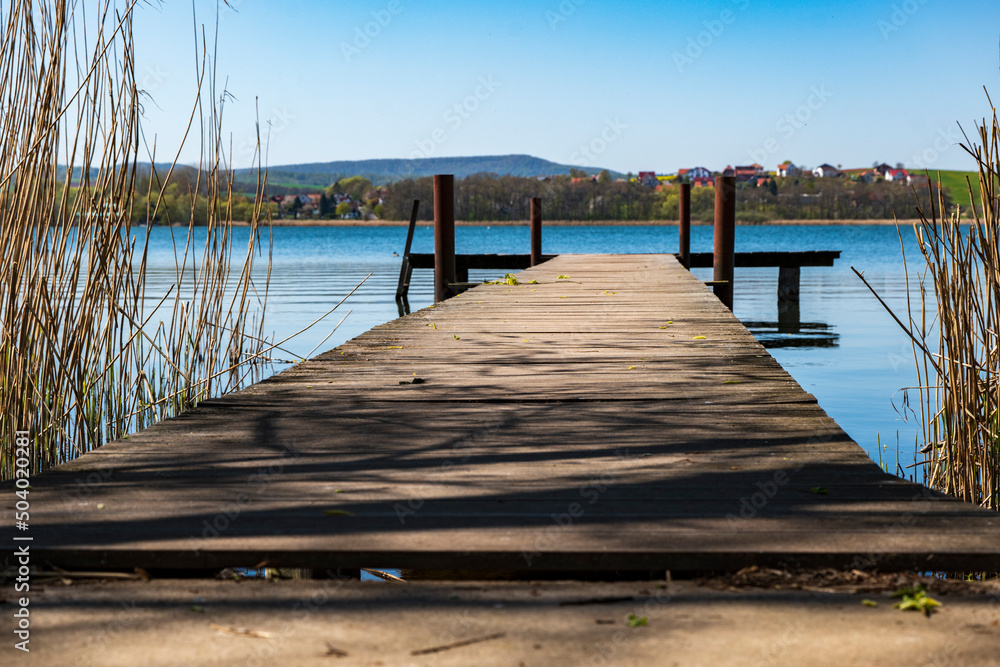 Obraz premium Ground-level shot of a jetty protruding into a blue lake