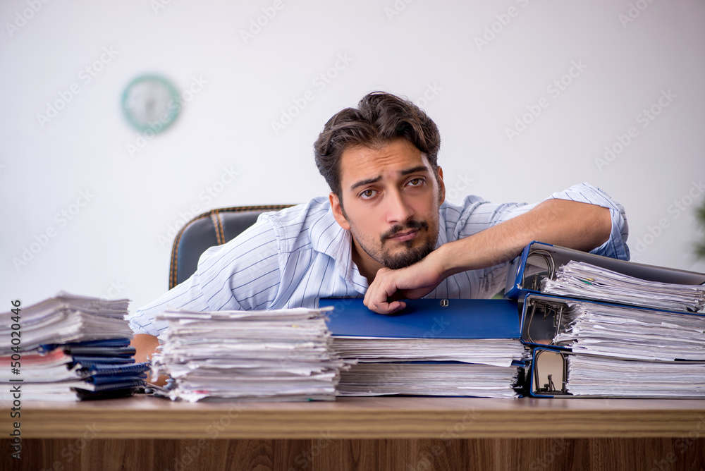 Young male employee and too much work in the office Young male employee and too much work in the office