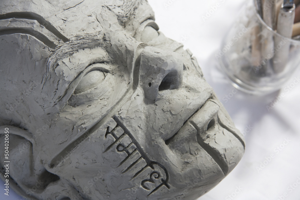 Sculpture of male face in clay. Engraving in Sanskrit script, "Samadhi