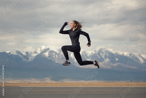 Sports girl jumping on the background of the mountains.