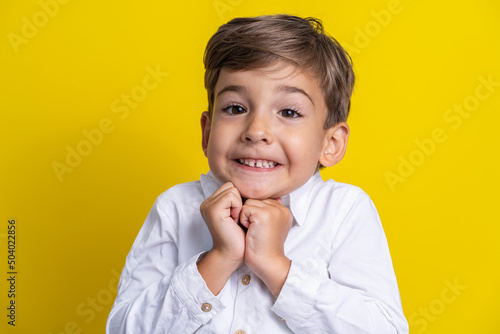 Front view of small caucasian boy four years old standing in front of yellow background studio shot child making poses looking to the camera surprised or impatient copy space photo