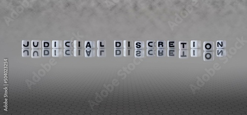 judicial discretion word or concept represented by black and white letter cubes on a grey horizon background stretching to infinity photo