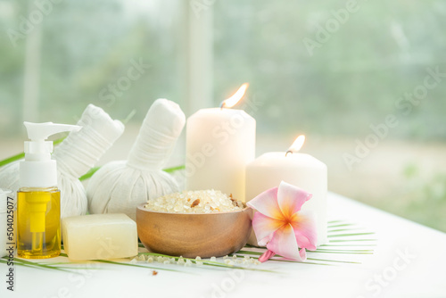 Coconut oil, tropical leaves and fresh coconuts. Spa coconut products on light wooden background. Spa still life of organic cosmetics with coconuts on a light wooden background, body care concept.