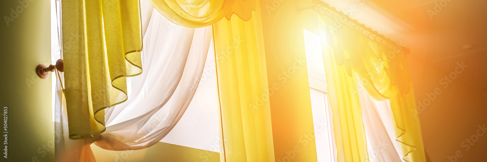 Sun is shines through thin yellow curtain hanging on window at home or hotel room